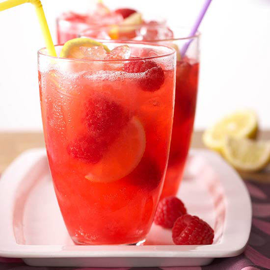 a glass of red lemonade with raspberries inside