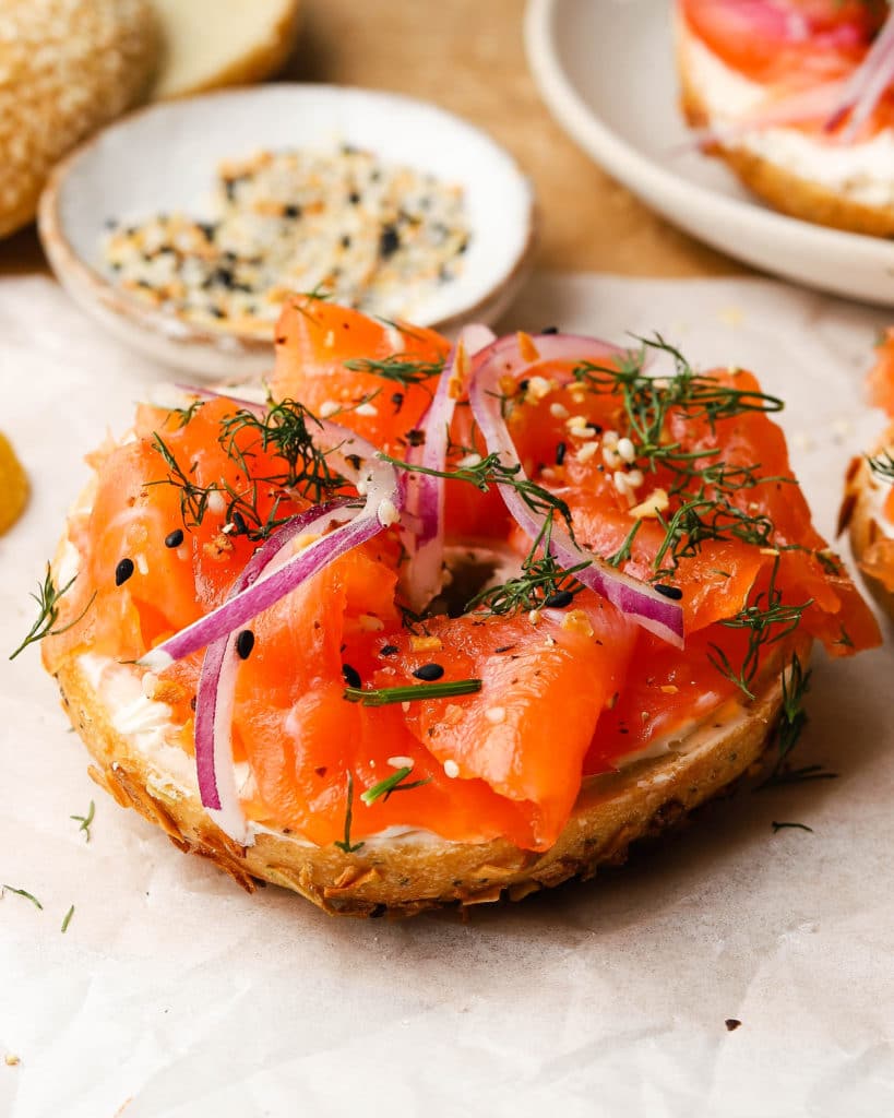salmon on top of a bagel with red onions and green garnishes